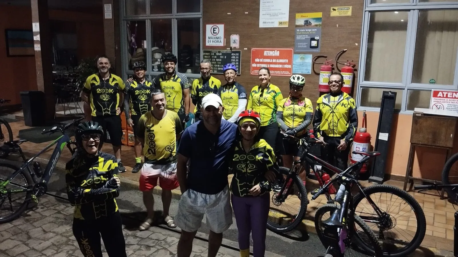 Turma do grupo com suas bikes reunida na frente de um prédio de tijolos